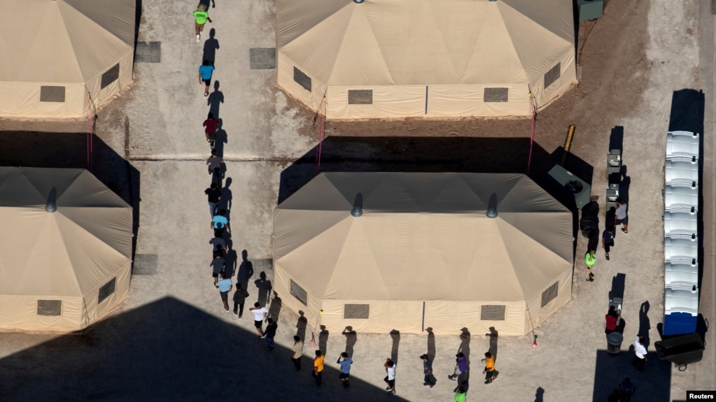 FILE - Immigrant children are led by staff in single file between tents at a detention facility next to the Mexican border in Tornillo, Texas, June 18, 2018.