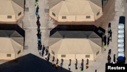 FILE - Immigrant children are led by staff in single file between tents at a detention facility next to the Mexican border in Tornillo, Texas, June 18, 2018.