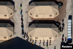 Immigrant children are led by staff in single file between tents at a detention facility next to the Mexican border in Tornillo, Texas, June 18, 2018.