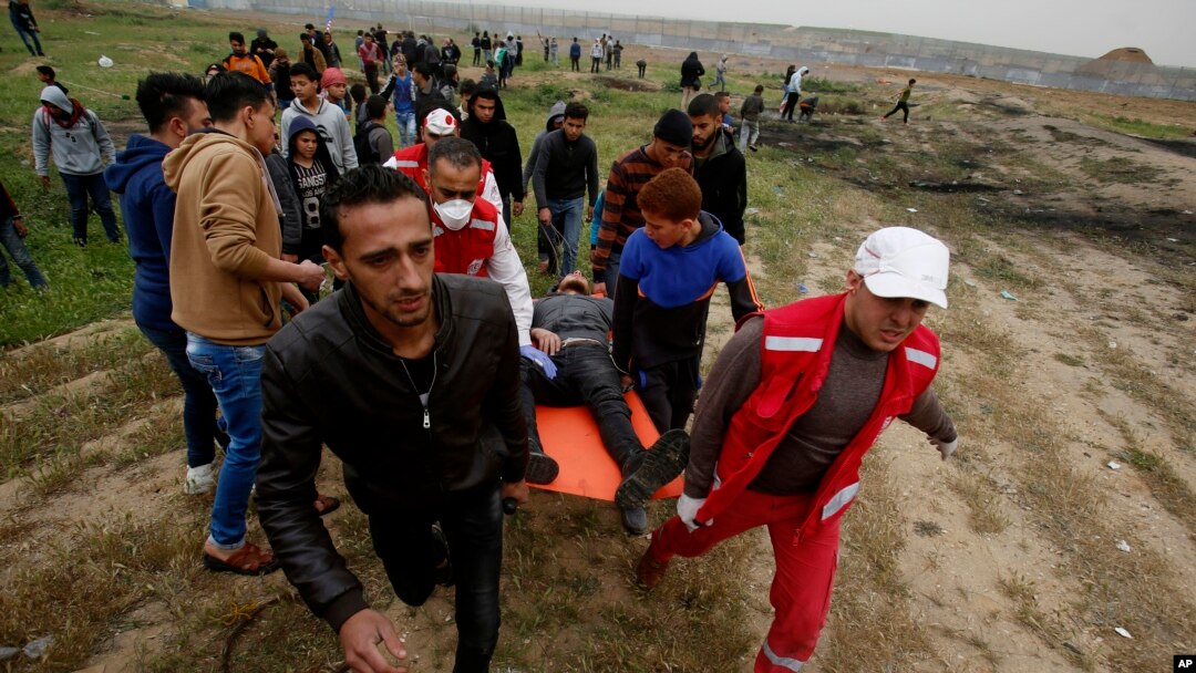 Medics and protesters evacuate a youth who was shot by Israeli troops near the Gaza Strip's border with Israel while marking first anniversary of Gaza border protests east of Gaza City, March 30, 2019.