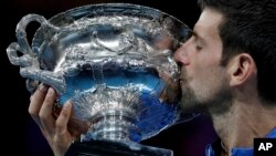 Serbia's Novak Djokovic kisses his trophy after defeating Spain's Rafael Nadal in the men's singles final at the Australian Open tennis championships in Melbourne, Australia, Jan. 27, 2019. 
