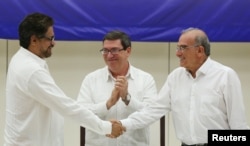 FILE - Lead FARC negotiator Ivan Marquez, left, and lead Colombian government negotiator Humberto de la Calle shake hands while Cuba's Foreign Minister Bruno Rodriguez looks on after the signing of a final peace deal in Havana, Cuba, Aug. 24, 2016.