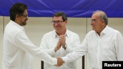 Lead FARC negotiator Ivan Marquez, left, and lead Colombian government negotiator Humberto de la Calle shake hands while Cuba's Foreign Minister Bruno Rodriguez looks on after the signing of a final peace deal in Havana, Cuba, Aug. 24, 2016.