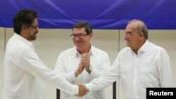 Глава делегации ФАРК, Иван Маркес, (слева) и представитель Колумбийского правительства Умберто де ла Калле пожимают руки после подписания мирного соглашения. Гавана, Куба, 24 августа 2016.
