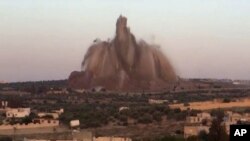 FILE - This file image made from video posted May 14, 2014, by Shaam News Network (SNN), an anti-Bashar Assad activist group, which has been verified and is consistent with other AP reporting, shows the bombing of a large amount of explosives in a tunnel under a military base in Wadi Deif, northwest Syria.