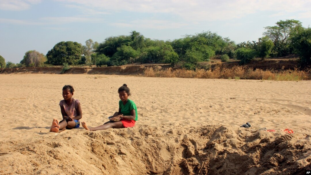 FILE - In this Nov. 11, 2020, photo, children sit by a water hole in a dry river bed in the remote village of Fenoaivo, Madagascar. 