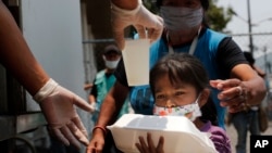 A child gets a meal outside the Iztapalapa hospital in Mexico City, on May 20, 2020, as part of a program for people who have not been able to work because of the COVID-19 pandemic.