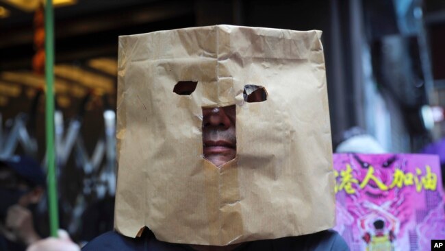Un manifestante utiliza una bolsa de papel para cubrirse el rostro durante una marcha en Hong Kong, el domingo 6 de octubre de 2019. (AP Foto/Kin Cheung)