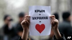 Một người Tatar Ukraina giơ tấm poster với dòng chữ 'Crimea + Ukraina = Trái tim' trong một cuộc biểu tình phản đối trước toà nhà chính phủ ở Simferopol, Crimea, Ukraina, 26/2/2014