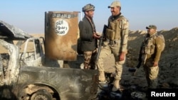 Iraqi security forces stand on a destroyed vehicle belonging to Islamic State militants on the outskirt of Ramadi, Dec. 21, 2014.