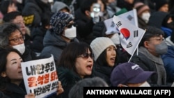 Manifestantes pedindo a destituição do Presidente da Coreia do Sul, Yoon Suk Yeol, à porta da Assembleia Nacional, em Seul, 14 de dezembro 2024