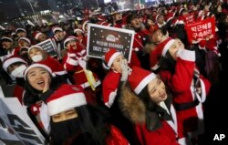 People wearing Santa Claus costumes shout during a rally calling for South Korean President Park Geun-hye to step down in Seoul, South Korea, Dec. 24, 2016.