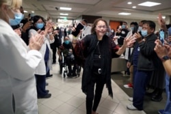 Intensive Care Unit Nurse Merlin Pambuan, 66, is cheered by hospital staff as she walks out of the hospital where she spent eight months with COVID-19, at Dignity Health – St. Mary Medical Center, in Long Beach, California, Dec. 21, 2020.
