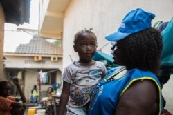 Agnes Anjack Alphonse, a UNICEF community health volunteer, tells a little girl that she needs to get vaccinated against measles. (Chika Oduah/VOA)