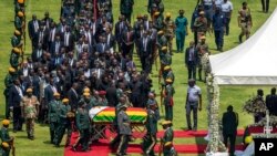 El féretro del expresidente Robert Mugabe, cubierto por la bandera nacional y seguido por familiares y dignatarios, llega para un funeral de Estado al Estadio Nacional Deportivo en Harare, Zimbabue, el sábado.