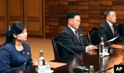 In this photo provided by South Korea Unification Ministry, the head of North Korean delegation Kwon Hyok Bong, center, and Hyon Song Wol, head of the Moranbong Band, left, sit during a meeting with South Korean officials at the North side of Panmunjom, N
