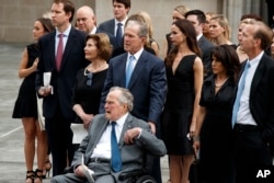 Former President George W. Bush and his father former President George H.W. Bush watch as the casket of former first lady Barbara Bush is loaded into a hearse at St. Martin's Episcopal church, April 21, 2018, in Houston