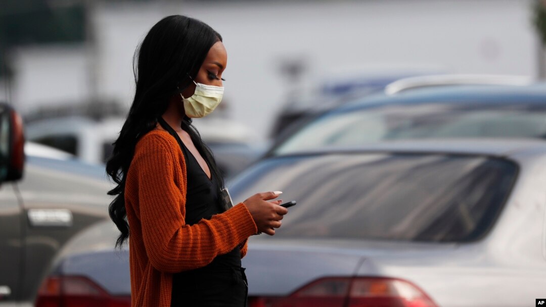 A shopper walks through the Target parking lot in northeast Jackson, Miss., where Mississippi Department of Health released figures show African Americans are being disproportionately affected by the coronavirus