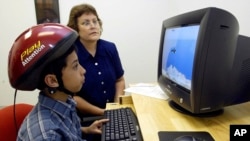 FILE - An 8-year-old boy concentrates on a computer screen as he uses a special helmet — an ADHD intervention device — with an instructor's help at a learning center in Greensboro, N.C.