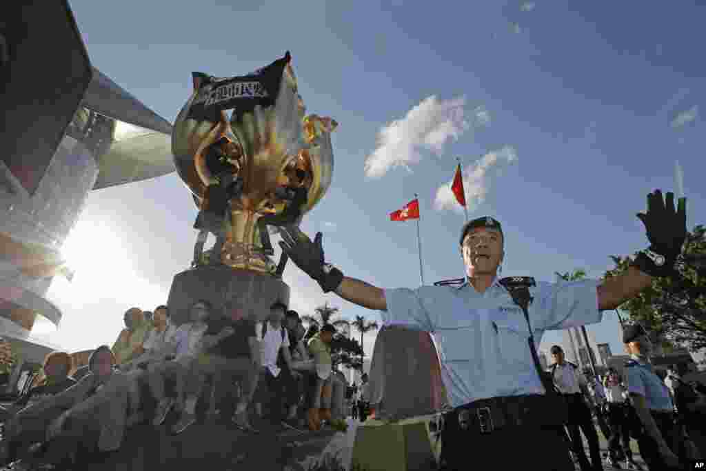 在香港湾仔金紫荆广场（ Golden Bauhinia Square），警察阻止抗议者爬上金紫荆雕塑。雕塑上已经有不少人，雕塑顶部挂着黑布，写着标语&ldquo;无条件释放刘晓波&rdquo;和&ldquo;香港市民要真普选&rdquo;（2017年6月28日）。这座大型雕塑是1997年香港回归中国时北京送的礼物。