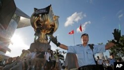 A policeman tries to stop members of the Demosisto political party and other pro-democracy activists from climbing a giant flower statue given to Hong Kong from Beijing in 1997 in Golden Bauhinia Square, Hong Kong, June 28, 2017.