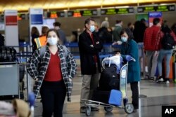 Travelers wear masks as they wait to drop their luggage at Los Angeles International Airport, March 14, 2020. A U.S. travel ban is likely to further roil the airline industry as bookings decline because of coronavirus fears.