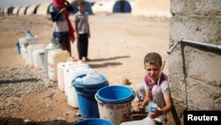 FILE - A displaced Iraqi boy fills a bottle with water in Jada camp south of Mosul, Iraq Aug. 9, 2017. 