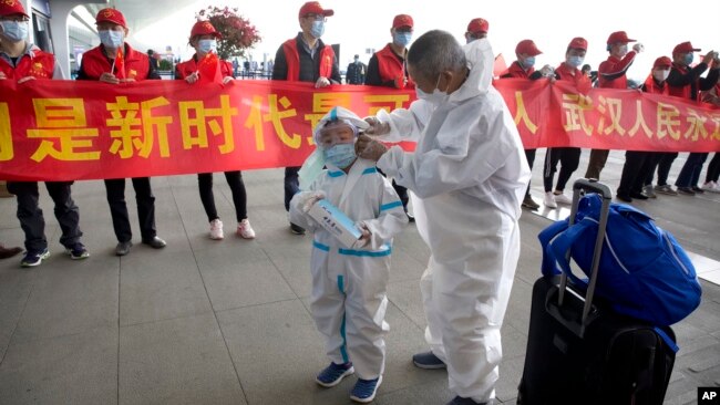 武汉解封,天河国际机场的旅客站在庆祝的标语横幅旁。(2020年4月8日)