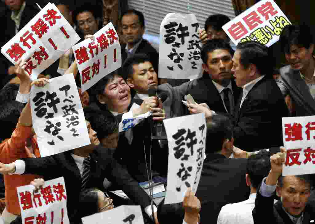 Opposition lawmakers surround Yasukazu Hamada (r) chairman of the lower house special committee on security legislation, as Hamada continues the committee proceedings at the parliament in Tokyo.