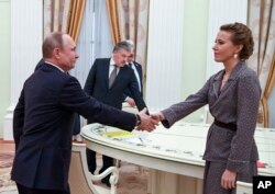 Russian President Vladimir Putin, left, greets Ksenia Sobchak, right, during his meeting with opposition candidates who ran against him in Sunday's presidential election.