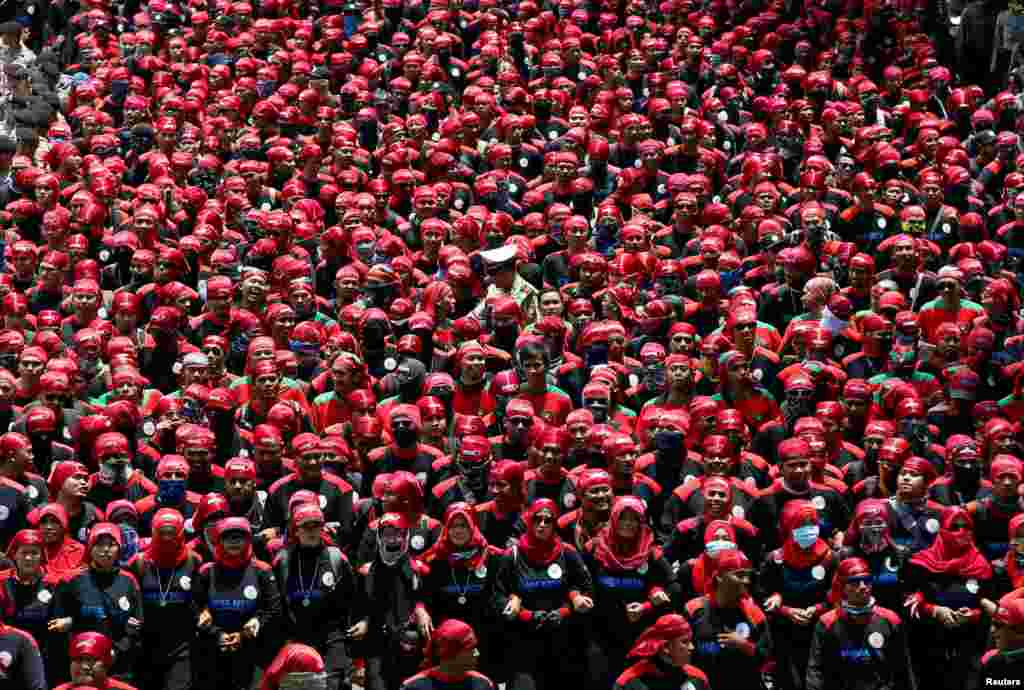 A police officer walks in the middle of Indonesian union workers protesting against a government tax amnesty, on their way to the presidential palace in Jakarta.