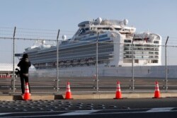 FILE - A photographer takes photos near the quarantined Diamond Princess cruise ship anchored at a port in Yokohama, near Tokyo, Feb. 21, 2020.