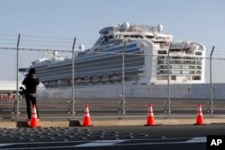 A photographer takes photos near the quarantined Diamond Princess cruise ship anchored at a port in Yokohama, near Tokyo, Feb. 21, 2020.
