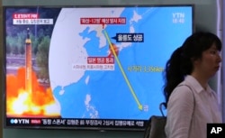 A woman passes by a TV screen showing a local news program reporting on North Korea's threats to strike Guam with missiles at the Seoul Train Station in Seoul, South Korea, Aug. 10, 2017.