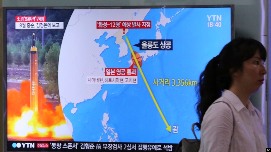 Seorang perempuan melewati layar TV di stasiun Kereta Seoul, yang sedang menyiarkan berita Korea Utara mengancam menyerang Guam dengan misil. 10 Agustus 2017. 