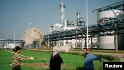 FILE - Workers walk past Jilin Fuel, one of the world's largest fuel ethanol plants, near the provincial capital Changchun of China's northeast Jilin province, early September 2003.