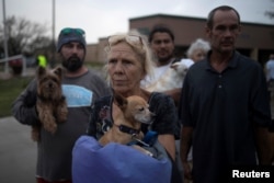 FILE - Julie holds her dog Pee-wee as they stand in line to be evacuated to Austin after losing their home to Hurricane Harvey in Rockport, Texas, Aug. 26, 2017.