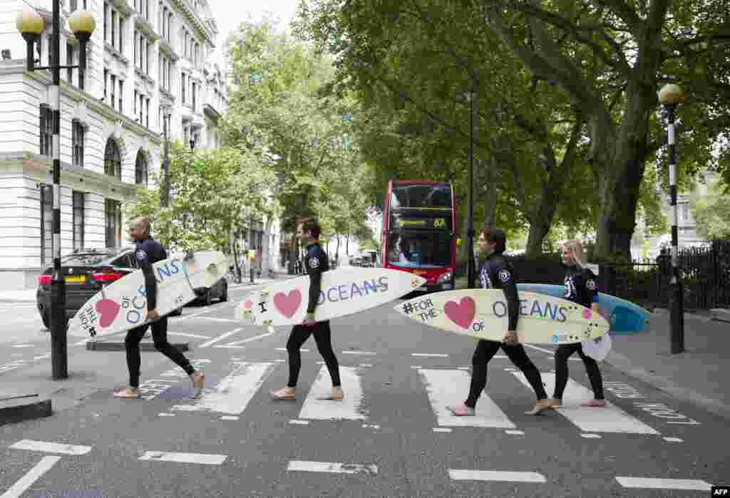 Climate change campaigners in wetsuits holding surfboards cross the road by the Houses of Parliament in London ahead of a mass lobby to urge members of parliament to back strong action on climate change.