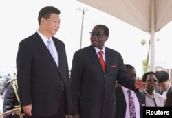 Chinese President Xi Jinping talks with Zimbabwean President Robert Mugabe on arrival for a state visit in Harare, Zimbabwe, Dec. 1, 2015.