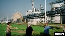 FILE - Workers walk past Jilin Fuel, one of the world's largest fuel ethanol plants, near the provincial capital Changchun of China's northeast Jilin province, early Sept. 2003.