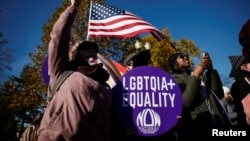 People hold flags and signs at a demonstration as the U.S. Supreme Court hears arguments over a Republican-backed ban in Tennessee on gender-affirming medical care for transgender minors, outside the court in Washington, Dec. 4, 2024. 