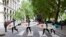 FILE - Climate change campaigners in wetsuits and holding surfboards cross the road by the Houses of Parliament, London, June 17, 2015.