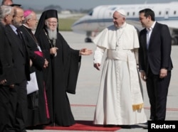 Greek Orthodox Ecumenical Patriarch Bartolomew I (L) and Greek Prime Minister Alexis Trispras (R) welcome Pope Francis as he arrived on the Greek Island of Lesbos for a visit aimed at supporting refugees and drawing attention to the front line of Europe'