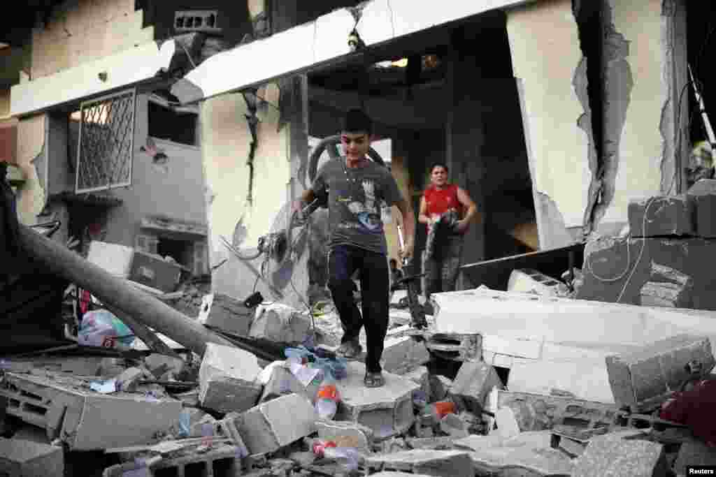 فلسطینی لڑکے حملے سے تباہ ہونے والے گھر سے اپنی اشیا نکال رہے ہیں۔ ۔