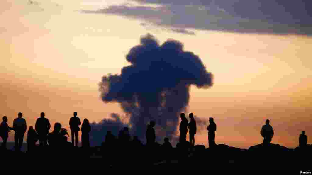 Turkish Kurds watch the smoke rises from Syrian town of Kobani near the Mursitpinar border crossing, on the Turkish-Syrian border in the southeastern town of Suruc, Sanliurfa province, Oct. 18, 2014.