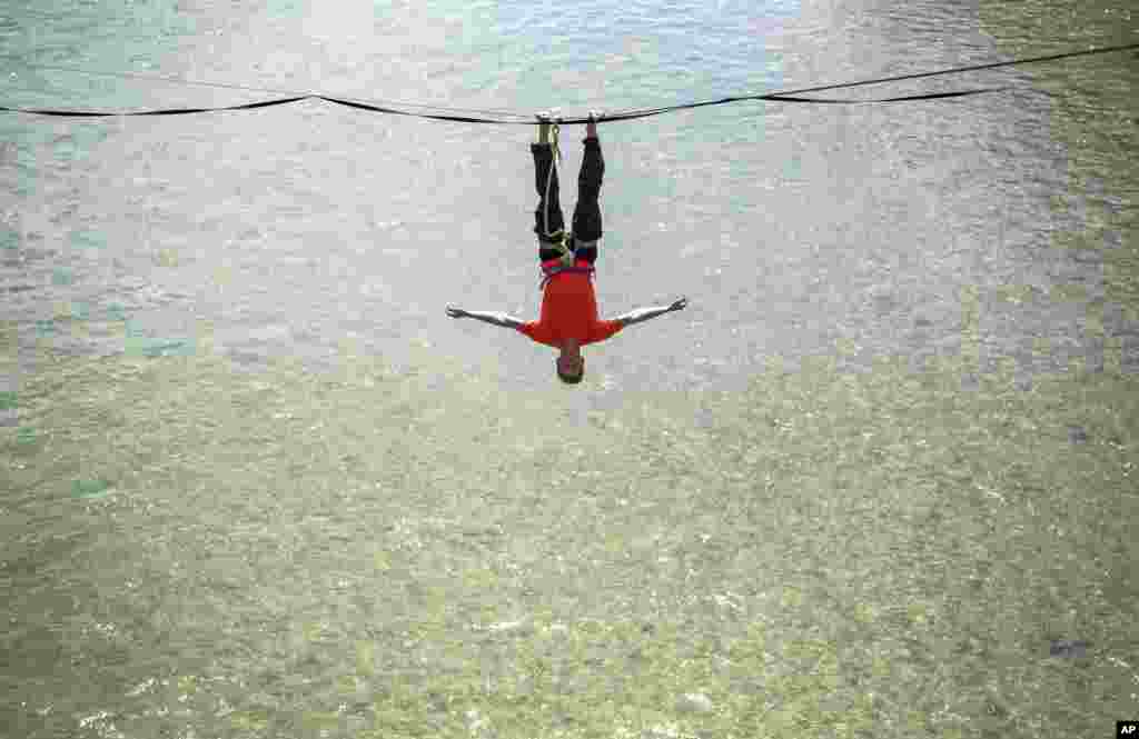 Slakliner Lukas Irmler hangs at a slack line as he performs over the river Isar in Munich, Germany.