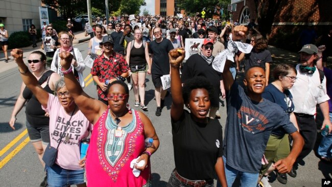 在维吉尼亚州夏洛茨维尔，反对种族主义的示威者沿着城市街道游行。