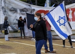 Seorang perempuan Israel mengenakan masker membawa bendera nasional saat dia memprotes apa yang mereka anggap sebagai ancaman terhadap demokrasi Israel. (Foto: AFP)