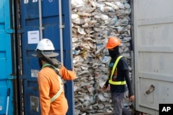 Para pekerja membuka kontainer berisi plastik yang tidak bisa didaur ulang yang ditahan otoritas pelabuhan Klang di Malaysia, 28 Mei 2019.