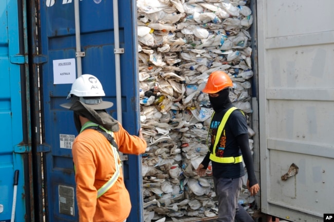 Para pekerja membuka kontainer berisi plastik yang tidak bisa didaur ulang yang ditahan otoritas pelabuhan Klang di Malaysia, 28 Mei 2019.